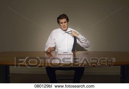 portrait of businessman sitting at desk loosening his tie View Large Photo Image Stock Image - portrait of businessman sitting at desk loosening his tie. Fotosearch