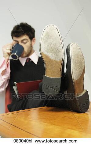 portrait of businessman sitting at table with his feet up holding mug and reading file View Large Photo Image Stock Image - portrait of businessman sitting at table with his feet up holding mug and reading file. Fotosearch