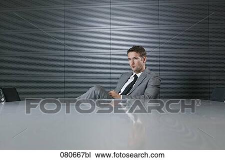 Stock Image - portrait of businessman sitting at conference table taking a break. Fotosearch