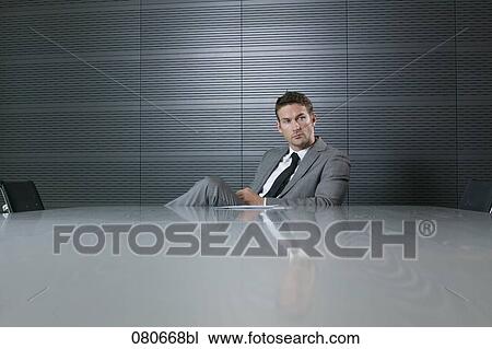 portrait of businessman sitting at conference table taking a break View Large Photo Image Stock Image - portrait of businessman sitting at conference table taking a break. Fotosearch