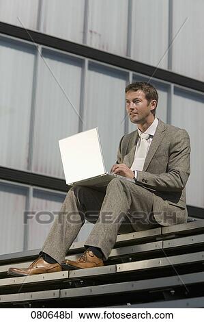 portrait of businessman sitting outdoors and working with laptop computer View Large Photo Image Stock Image - portrait of businessman sitting outdoors and working with laptop computer. Fotosearch