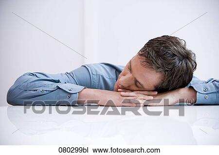 Stock Image - portrait of businessman sleeping with his head on the desk. Fotosearch