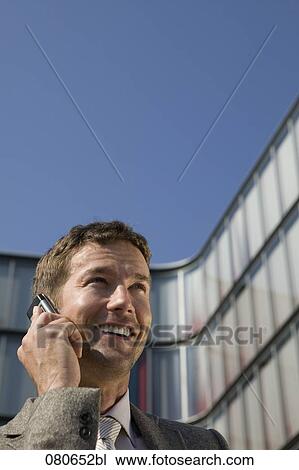 portrait of businessman talking on mobile phone in front of office building View Large Photo Image Stock Image - portrait of businessman talking on mobile phone in front of office building. Fotosearch