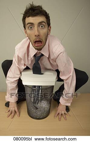 Stock Image - portrait of businessman whose tie is eaten by shredder. Fotosearch