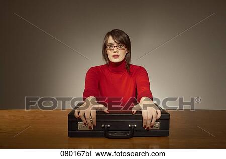 Stock Image - portrait of businesswoman sitting at desk with briefcase. Fotosearch