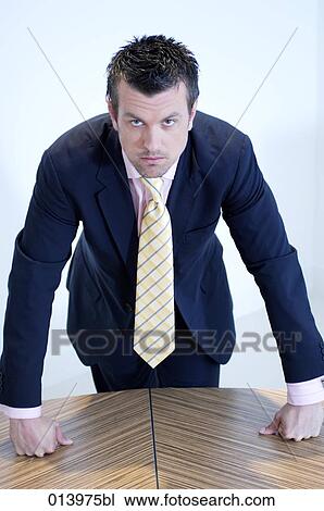 Stock Image - portrait of determined looking businessman leaning over table. Fotosearch