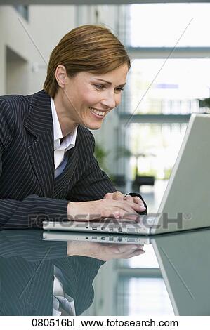 portrait of female executive sitting at table working with laptop computer View Large Photo Image Stock Image - portrait of female executive sitting at table working with laptop computer. Fotosearch