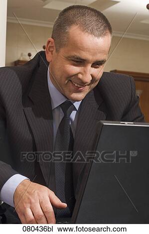 portrait of mature businessman working with laptop computer in hotel lobby View Large Photo Image Stock Image - portrait of mature businessman working with laptop computer in hotel lobby. Fotosearch