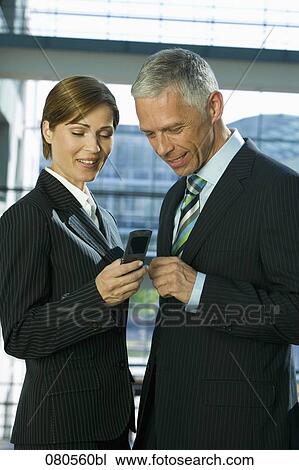 portrait of mature businesswoman and male colleague looking at mobile phone View Large Photo Image Stock Image - portrait of mature businesswoman and male colleague looking at mobile phone. Fotosearch