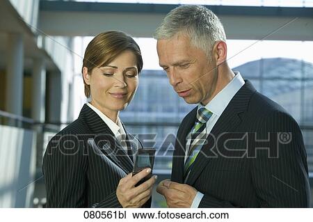 portrait of mature businesswoman and male colleague looking at mobile phone View Large Photo Image Stock Image - portrait of mature businesswoman and male colleague looking at mobile phone. Fotosearch