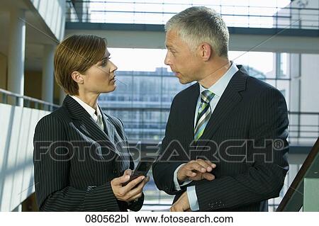 Stock Image - portrait of mature businesswoman and male colleague having discussion. Fotosearch
