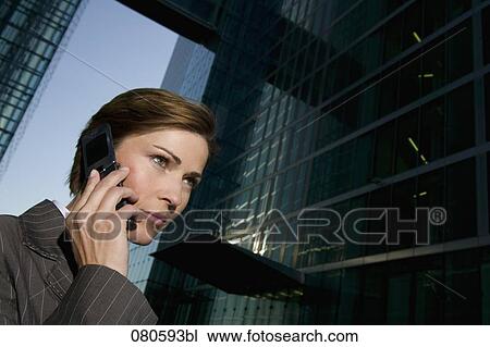 Stock Image - portrait of mature businesswoman talking on mobile phone in front of office building. Fotosearch