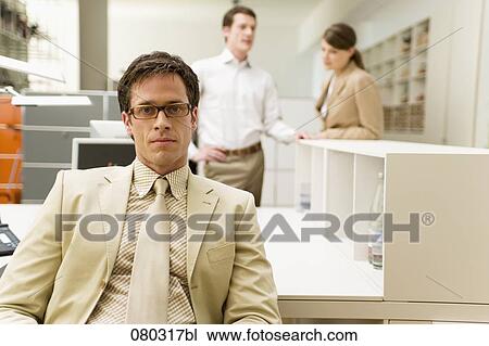 Stock Image - portrait of serious businessman sitting at desk. Fotosearch
