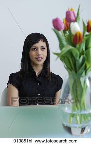 Stock Image - portrait of shy looking executive behind flowers. Fotosearch