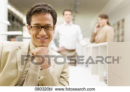 portrait of smiling businessman sitting at desk in office space View Large Photo Image Stock Image - portrait of smiling businessman sitting at desk in office space. Fotosearch