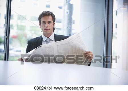 Stock Image - portrait of surprised businessman sitting at desk with business paper. Fotosearch