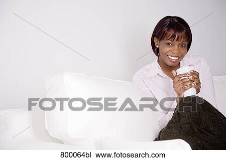 portrait of young black woman sitting on sofa and holding cup View Large Photo Image Stock Image - portrait of young black woman sitting on sofa and holding cup. Fotosearch