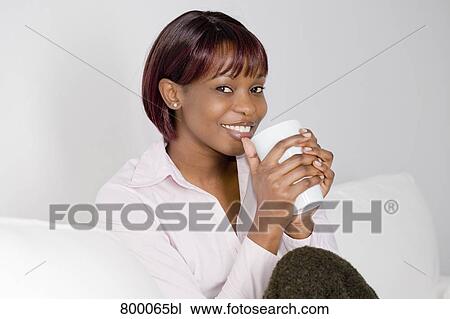 portrait of young black woman sitting on sofa and holding cup View Large Photo Image Stock Image - portrait of young black woman sitting on sofa and holding cup. Fotosearch