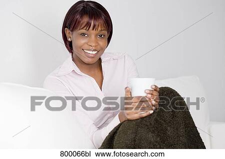 portrait of young black woman sitting on sofa and holding cup View Large Photo Image Stock Image - portrait of young black woman sitting on sofa and holding cup. Fotosearch