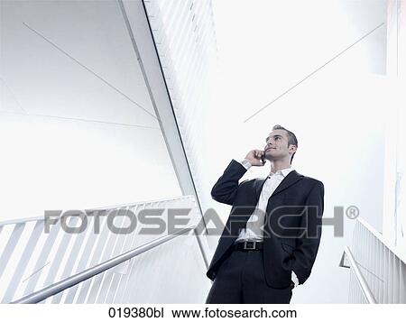 portrait of young businessman standing in staircase talking on mobile phone View Large Photo Image Stock Image - portrait of young businessman standing in staircase talking on mobile phone. Fotosearch
