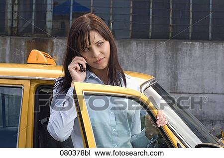 portrait of young businesswoman standing at open door of yellow taxi listening to mobile phone View Large Photo Image Stock Image - portrait of young businesswoman standing at open door of yellow taxi listening to mobile phone. Fotosearch