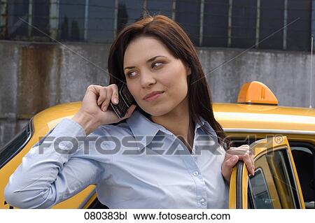 portrait of young businesswoman standing at open door of yellow taxi listening to mobile phone View Large Photo Image Stock Image - portrait of young businesswoman standing at open door of yellow taxi listening to mobile phone. Fotosearch