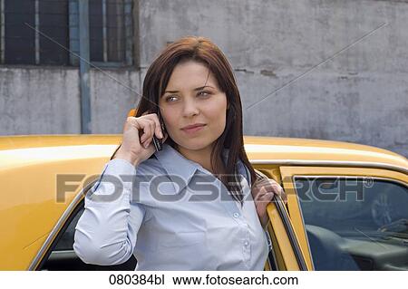 portrait of young businesswoman standing at open door of yellow taxi listening to mobile phone View Large Photo Image Stock Image - portrait of young businesswoman standing at open door of yellow taxi listening to mobile phone. Fotosearch