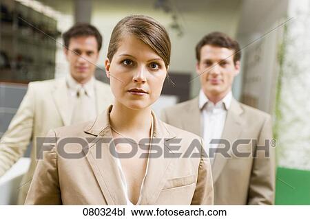 Stock Image - portrait of young businesswoman with two male colleagues in the background. Fotosearch