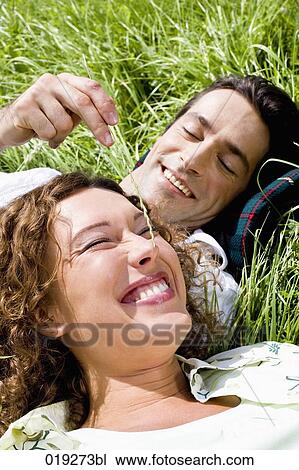 Stock Image - portrait of young couple playing in grass. Fotosearch