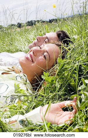 Stock Image - portrait of young couple relaxing in grass. Fotosearch