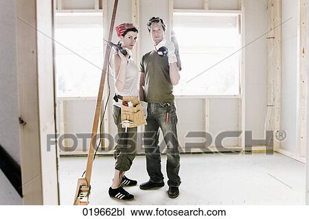 Stock Image - portrait of young couple standing in construction site of new home. Fotosearch