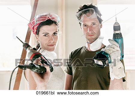 Stock Image - portrait of young couple with electric drills. Fotosearch