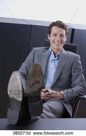 portrait of young entrepreneur sitting with his feet on desk View Large Photo Image Stock Image - portrait of young entrepreneur sitting with his feet on desk . Fotosearch