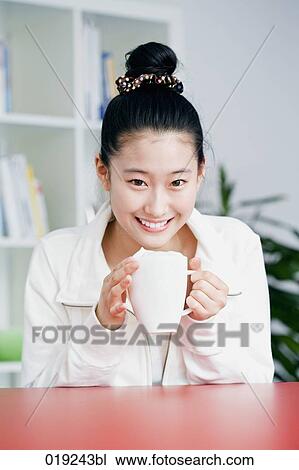 Stock Image - portrait of young japanese girl holding cup. Fotosearch