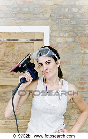 portrait of young woman holding sanding machine View Large Photo Image Stock Image - portrait of young woman holding sanding machine. Fotosearch