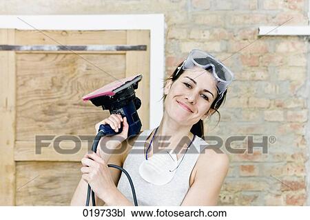 portrait of young woman holding sanding machine View Large Photo Image Stock Image - portrait of young woman holding sanding machine. Fotosearch