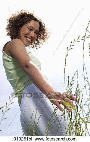 portrait of young woman standing on meadow touching grass View Large Photo Image Stock Image - portrait of young woman standing on meadow touching grass. Fotosearch