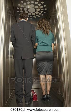 rear view of businessman and female colleague standing in elevator together View Large Photo Image Stock Image - rear view of businessman and female colleague standing in elevator together. Fotosearch