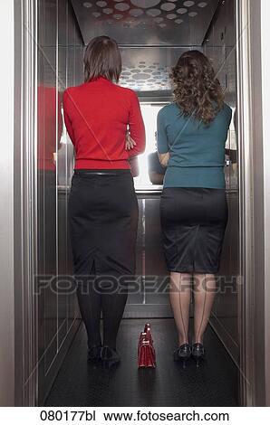 rear view of two businesswomen standing in elevator together View Large Photo Image Stock Image - rear view of two businesswomen standing in elevator together. Fotosearch