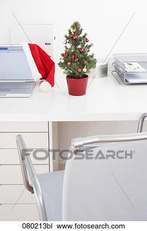still life of little christmas tree and santa claus hat on office desk View Large Photo Image Stock Image - still life of little christmas tree and santa claus hat on office desk. Fotosearch