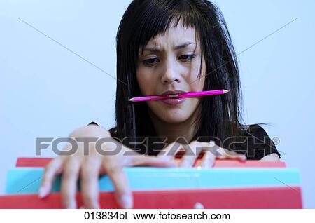 Stock Image - stressed young asian woman looking for a file. Fotosearch