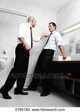 Stock Image - two businessmen having argument in public restroom. Fotosearch