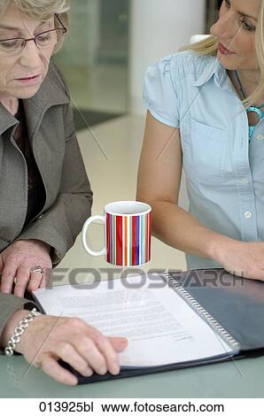 two businesswomen talking about document on table View Large Photo Image Stock Image - two businesswomen talking about document on table. Fotosearch