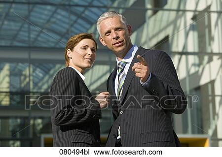 Stock Image - two mature business people having conversation in front of office building. Fotosearch