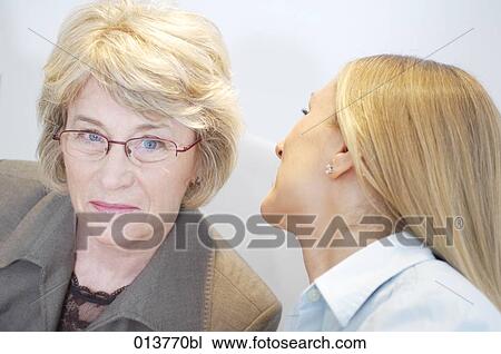 Stock Image - two women executives sharing a secret. Fotosearch
