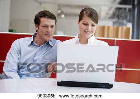 two young office workers sitting at laptop computer together View Large Photo Image Stock Image - two young office workers sitting at laptop computer together. Fotosearch