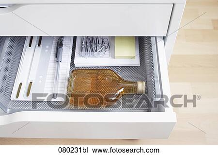 view into open desk drawer containing small alcohol bottle View Large Photo Image Stock Image - view into open desk drawer containing small alcohol bottle. Fotosearch