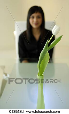 Stock Image - white flower on conference table with asian businesswoman in background. Fotosearch