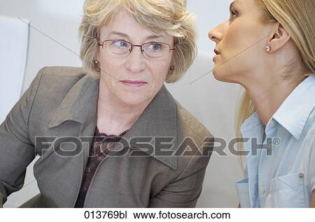 woman whispering into her female boss´s ear View Large Photo Image Stock Image - woman whispering into her female boss´s ear. Fotosearch