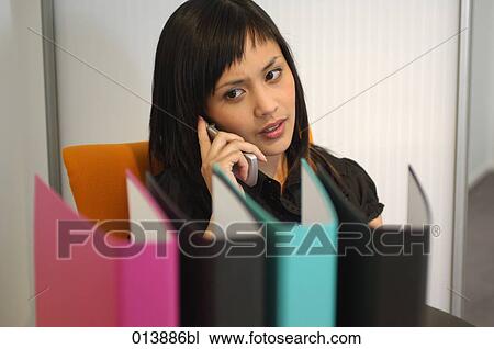 young asian businesswoman listening to mobile phone in office View Large Photo Image Stock Image - young asian businesswoman listening to mobile phone in office. Fotosearch